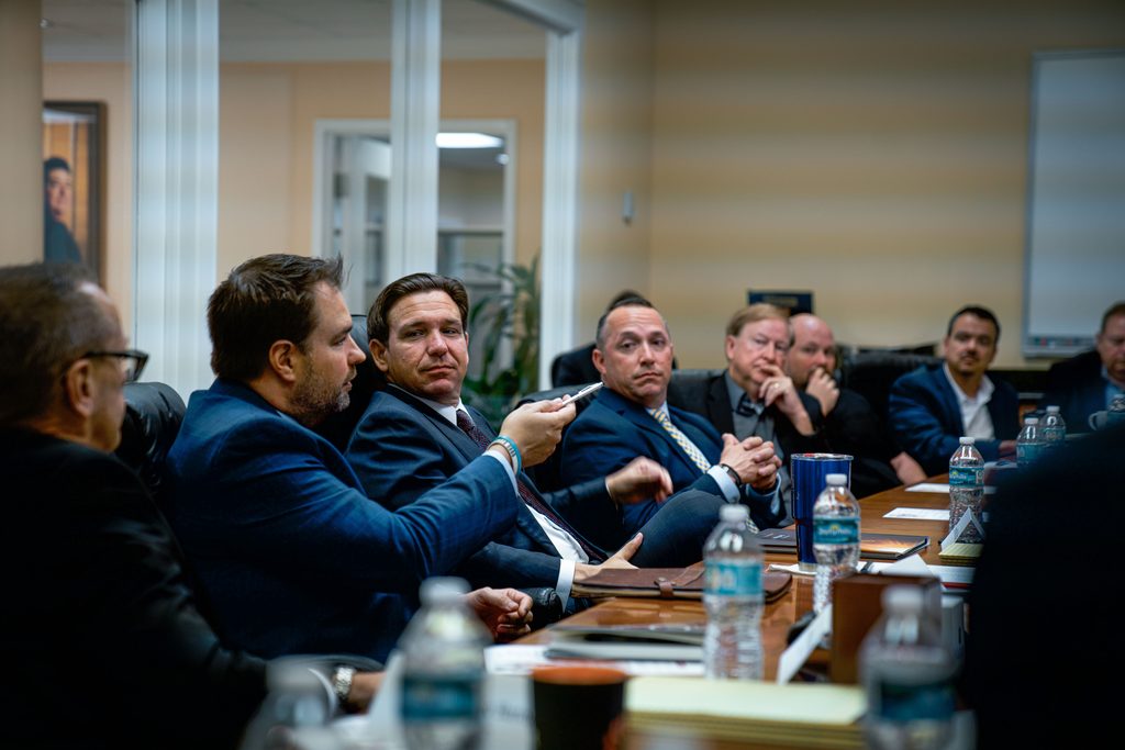 Erik Dellenback at a conference table with Governor DeSantis and Florida faith leaders
