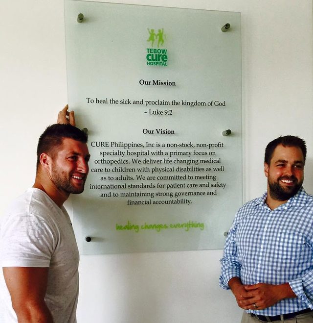Erik Dellenback and Tim Tebow beside the mission plaque at the Tebow CURE Hospital in Davao City